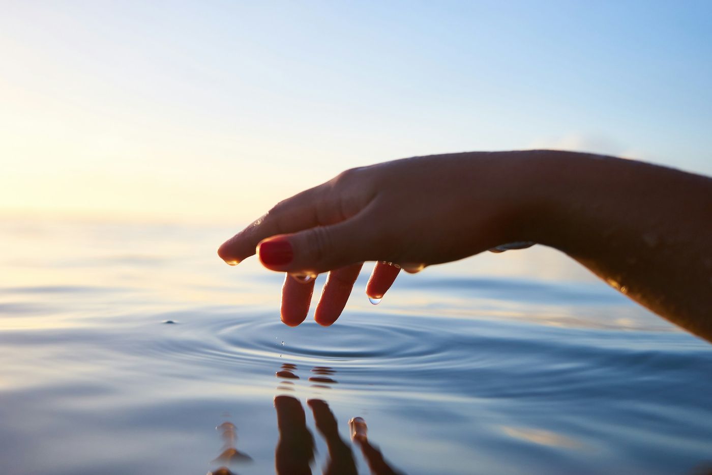 Hand, die sanft die Wasseroberfläche berührt